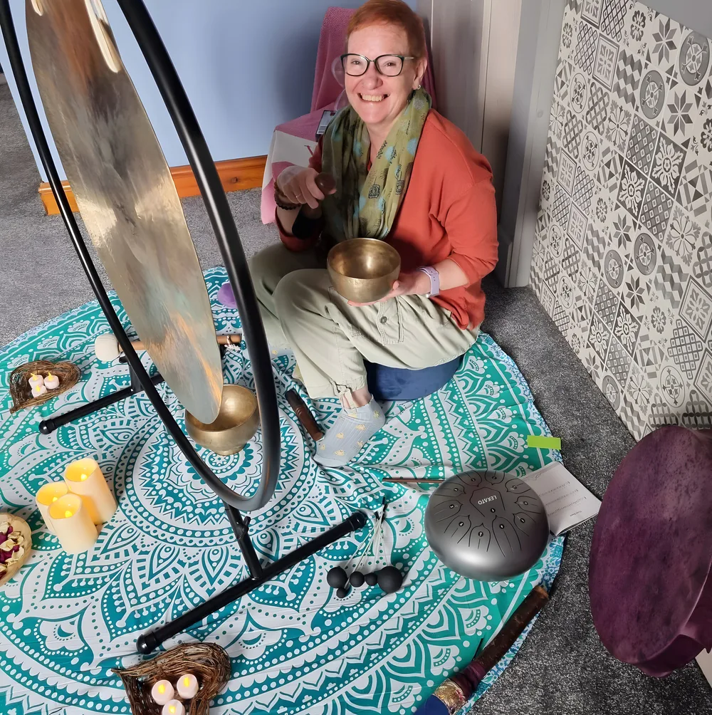Dawn Brown sitting beside her gong, holding a singing bowl.